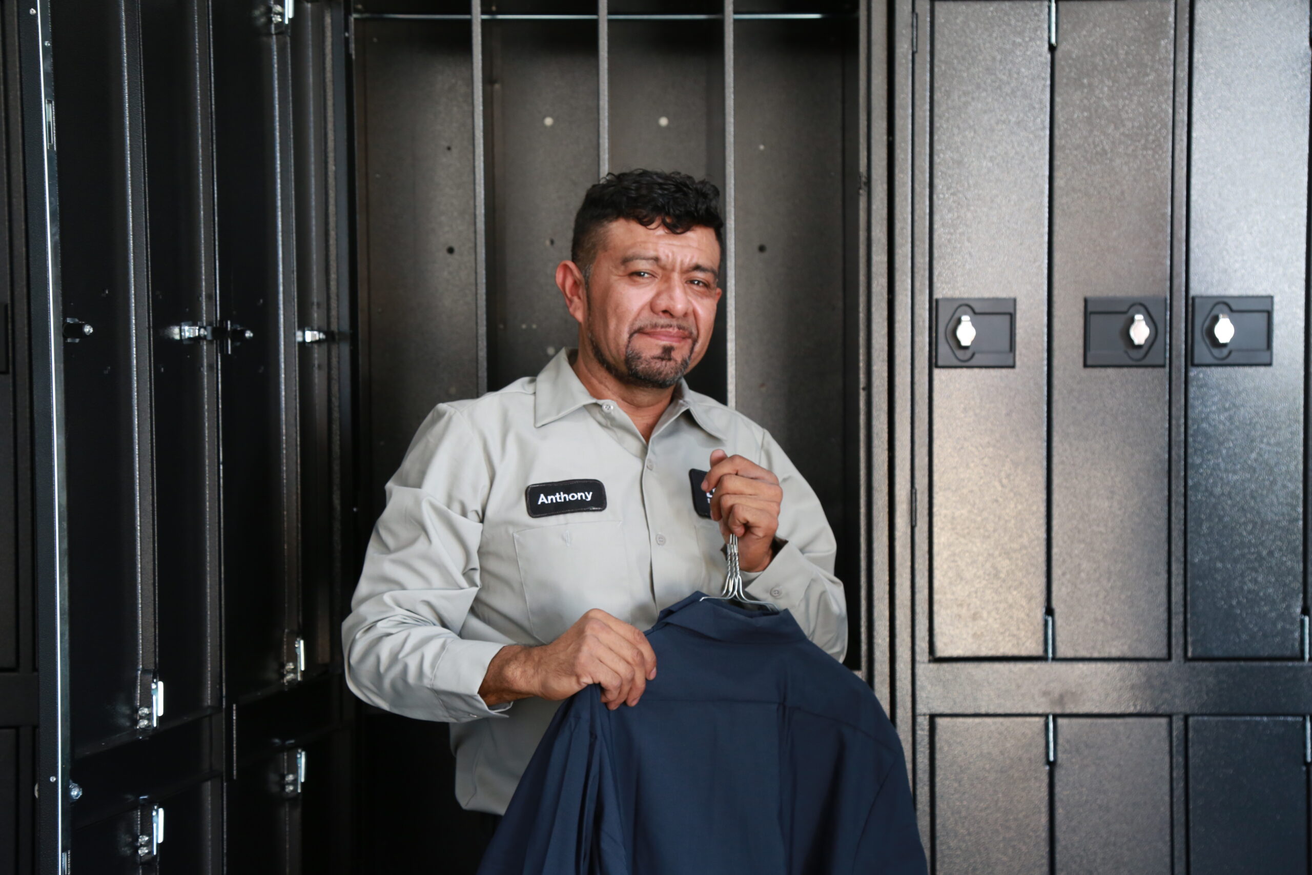 Employee organizing clean uniforms in a locker room Employee organizing clean uniforms in a locker room